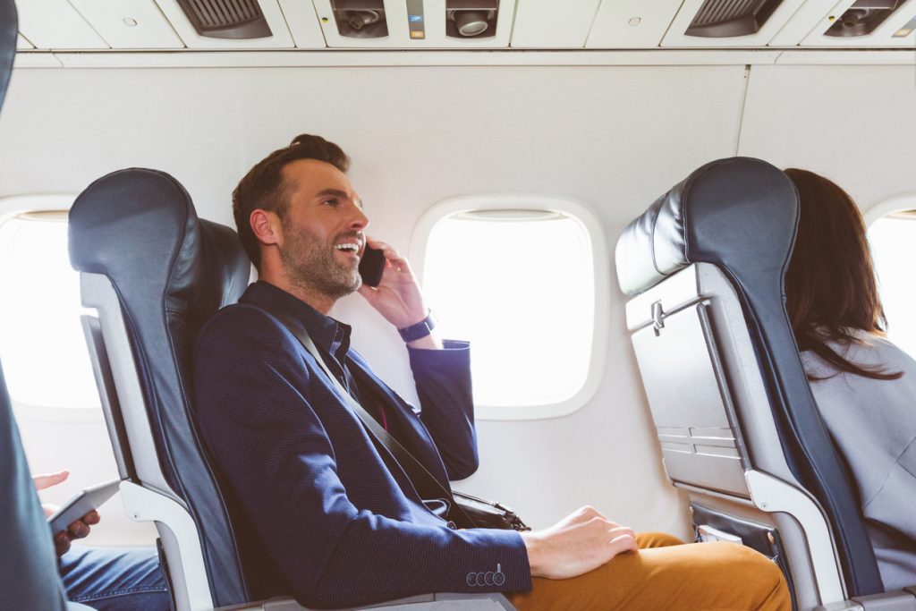 Businessman Talking On Phone In Plane | AdonisOne